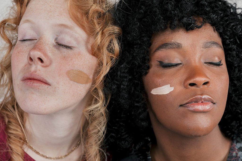 Closeup of African and Caucasian women with foundation on cheeks